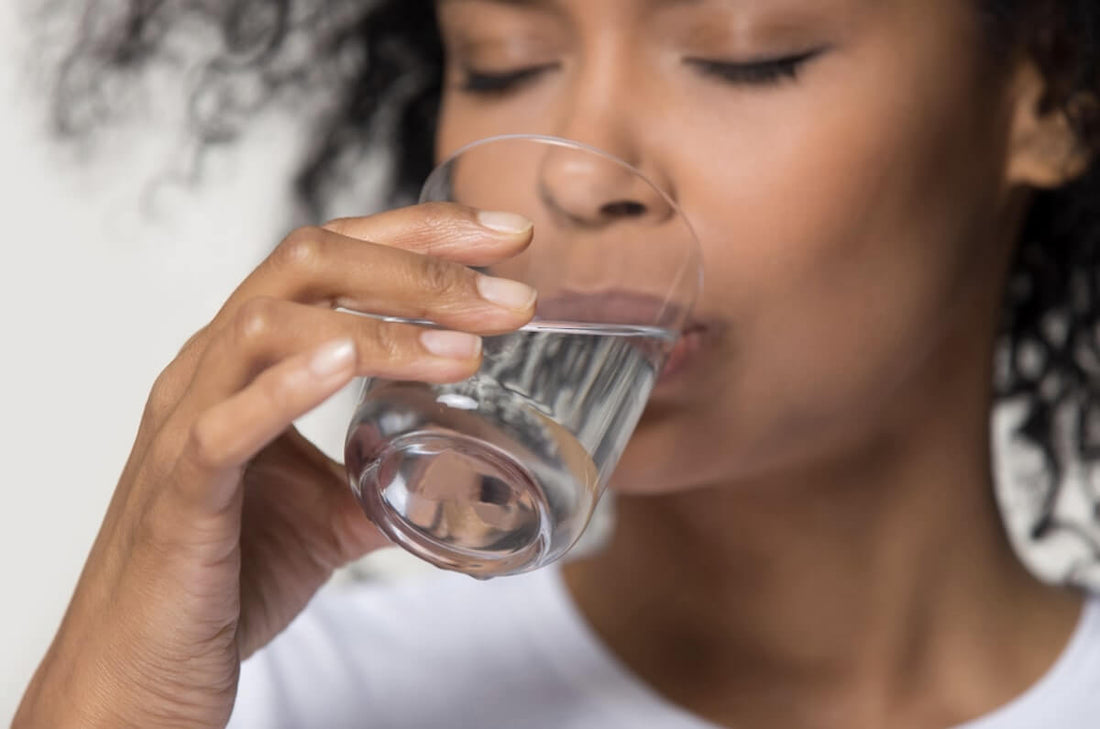 How much water should I drink to clear acne? - A lady drinking water